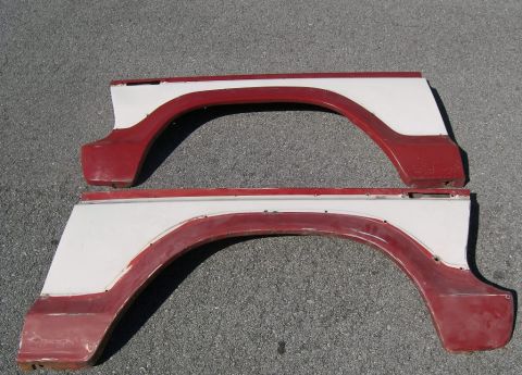 1974 Ford Bronco - Two red and white fender flares are shown laid out on an asphalt surface.