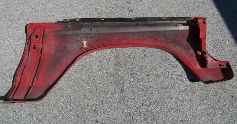 1974 Ford Bronco - A red fender flare, likely for a truck or SUV, is shown detached from a vehicle.