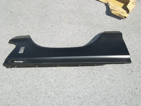 1974 Ford Bronco - A black fender panel is shown lying on a gray asphalt surface, with a cardboard box in the background.