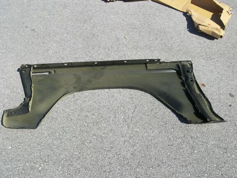 1974 Ford Bronco - A single fender part is shown lying on a grey asphalt surface.