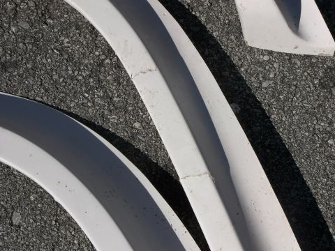1974 Ford Bronco - White fender flares are shown laid out on an asphalt surface, with a watermark for SUPERMOTORS.NET visible.