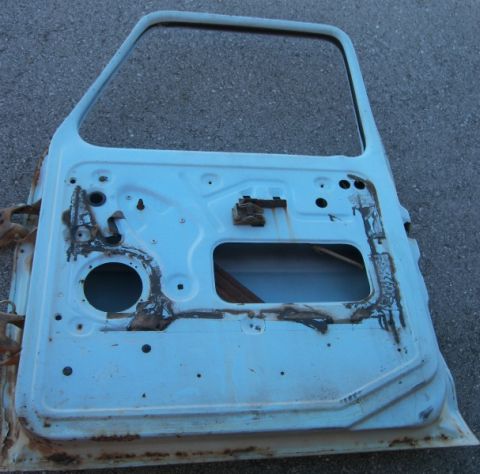 1974 Ford Bronco - The interior of a light blue car door shows significant rust and damage.