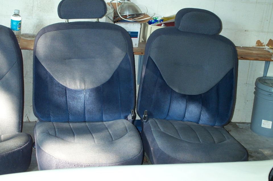 Two blue cloth bucket seats stored in a garage