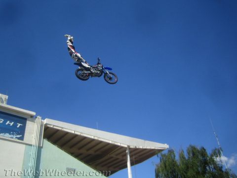 1990 Ford Bronco - motocross rider extends his body off a blue dirt bike during a high jump against a blue sky.