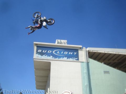 1990 Ford Bronco - freestyle rider rotates through a backflip on a dirt bike high above a Bud Light building sign.