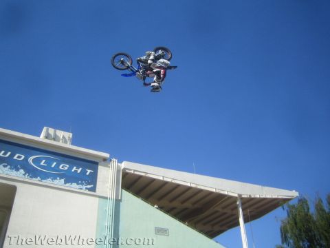 1990 Ford Bronco - motocross rider is fully inverted in a backflip on a dirt bike above a Bud Light stadium roof.