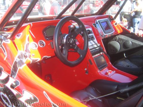 1990 Ford Bronco - interior of a red custom off-road buggy shows a flat dash with digital gauges, a center screen, shifter and bucket seats.