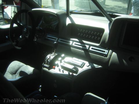 1990 Ford Bronco - interior of a custom vehicle shows a steering wheel, manual shifter, switch panels and suede bucket seats in harsh sunlight.