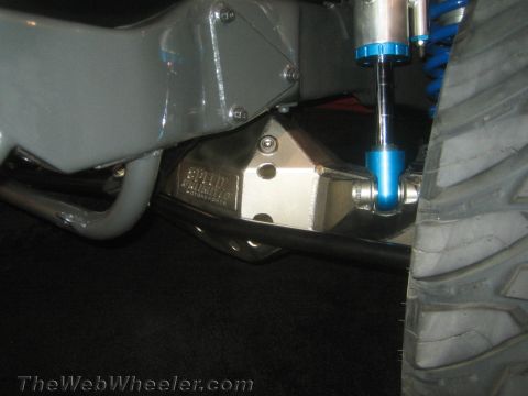 1990 Ford Bronco - close-up shows an aluminum suspension bracket with a blue-bodied coilover shock and a mud tire on a custom build.