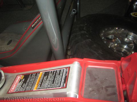 1990 Ford Bronco - Interior corner of an off-road build showing a red MasterCraft seat, a rear tire on a polished beadlock wheel, and a red Craftsman jack.