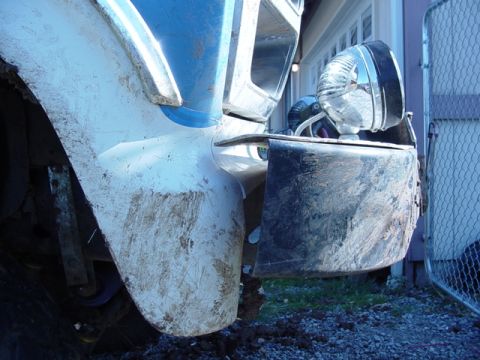1985 Ford Bronco - Mud-splattered front fender and bumper of a truck with a chrome headlight.
