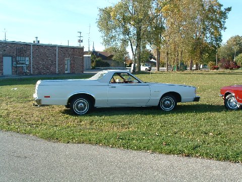 1973 Ford Ranchero - A white 1979 Ford Ranchero is parked on a grassy area next to a brick building, with another vehicle to its right.
