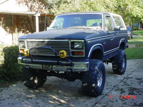 1984 Ford Bronco - This lifted Ford Bronco features oversized tires and a custom front bumper with yellow fog lights.