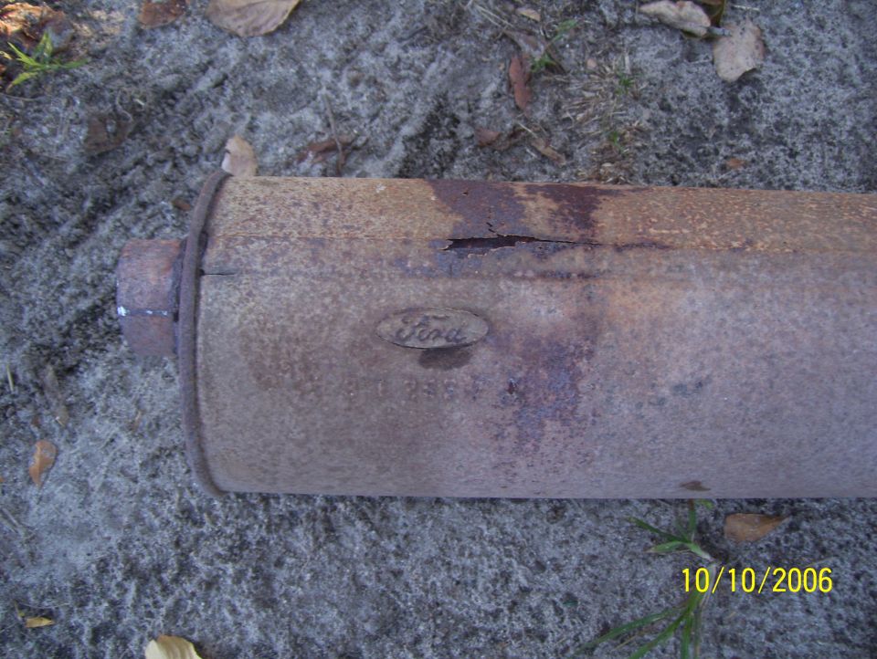 Rusty Ford exhaust muffler with visible Ford oval logo and part numbers