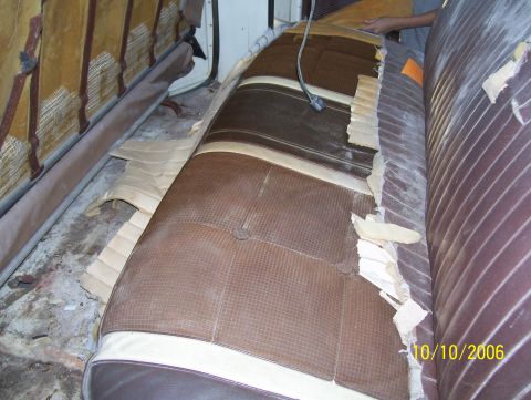 1978 Ford Bronco - Interior shot of a vehicle bench seat mid-reupholstery, with the brown vinyl and tan trim covers partially torn away to expose the burlap-c…