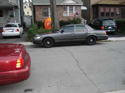 2000 Ford Crown Victoria - A gray 2000 Ford Crown Victoria is parked on a residential street next to other vehicles.