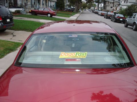 2000 Ford Crown Victoria - A red sedan is parked on a residential street, with a sticker on its rear window.