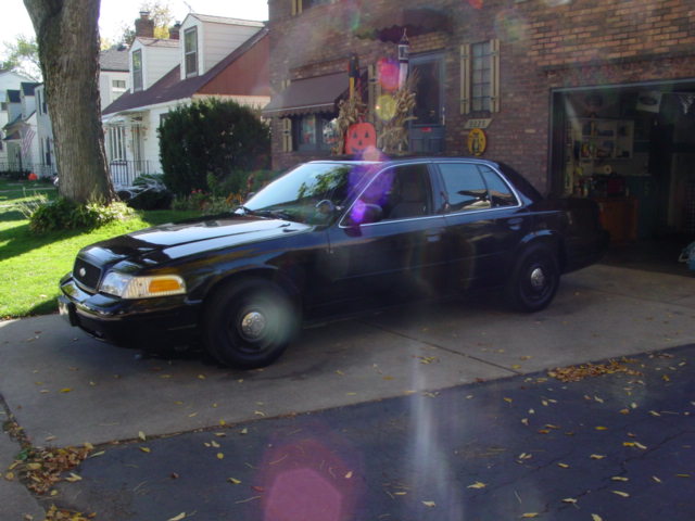 Black sedan parked in driveway, house and garage in background