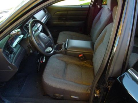 2003 Ford Crown Victoria - The interior of a 2003 Ford Crown Victoria, fabric seats and a dark dashboard.