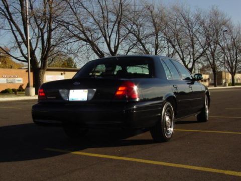 2003 Ford Crown Victoria - Rear view of a black 2003 Ford Crown Victoria parked in an empty lot on a sunny day.