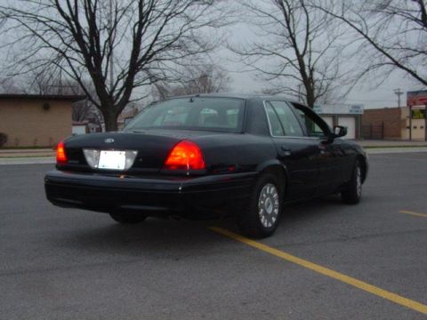 2003 Ford Crown Victoria - Rear view of a black 2003 Ford Crown Victoria sedan with full wheel covers parked on asphalt.