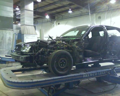 2003 Ford Crown Victoria - A black 2003 Ford Crown Victoria is shown on a repair lift with its front end disassembled.