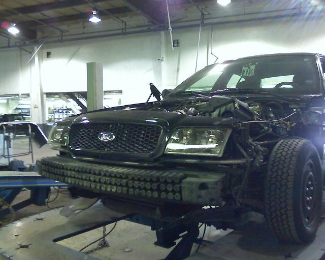 2003 Ford Crown Victoria front end with hood open, on a lift in a garage