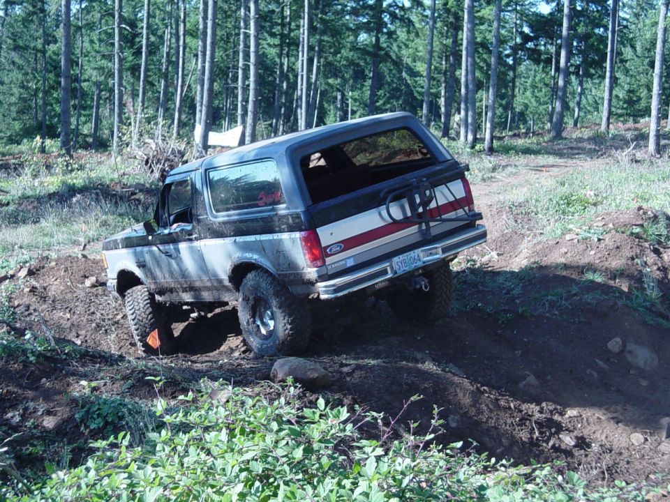 Ford Bronco climbing a dirt hill in a forest