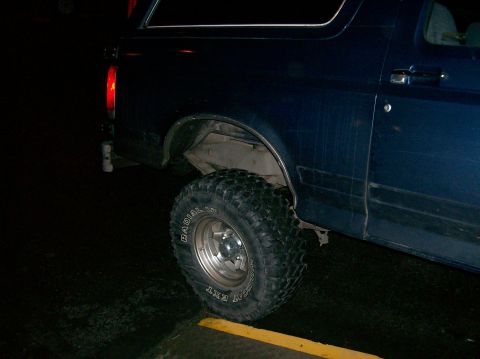 1988 Ford Bronco - Rear side view of a 1988 Ford Bronco with off-road tires. The fender and door are visible.