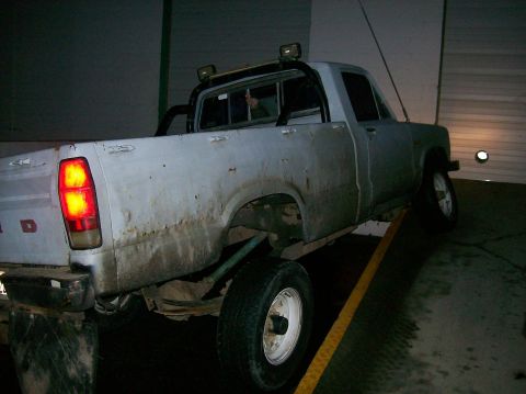 1988 Ford Bronco - Weathered pickup truck with brake lights illuminated, seen from the rear quarter angle.