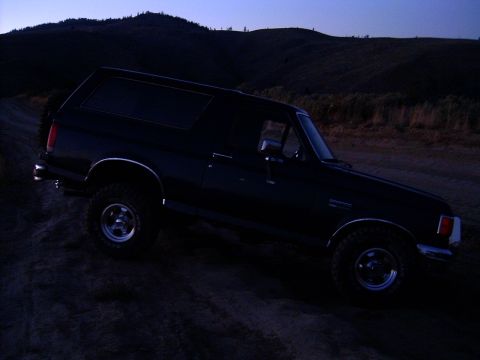 1988 Ford Bronco - 1988 Ford Bronco parked on a dirt road during twilight.