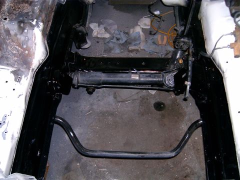 1978 Ford Mustang II - The engine bay of a car is shown during a repair, with the steering rack and sway bar clearly visible.