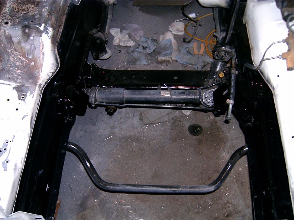 Car engine bay with steering rack and sway bar visible