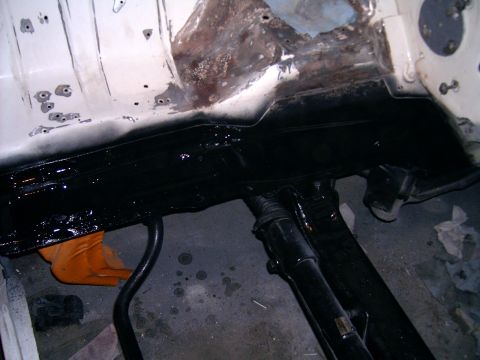 1978 Ford Mustang II - The underside of a vehicle shows areas of rust and new protective coating during a repair process.