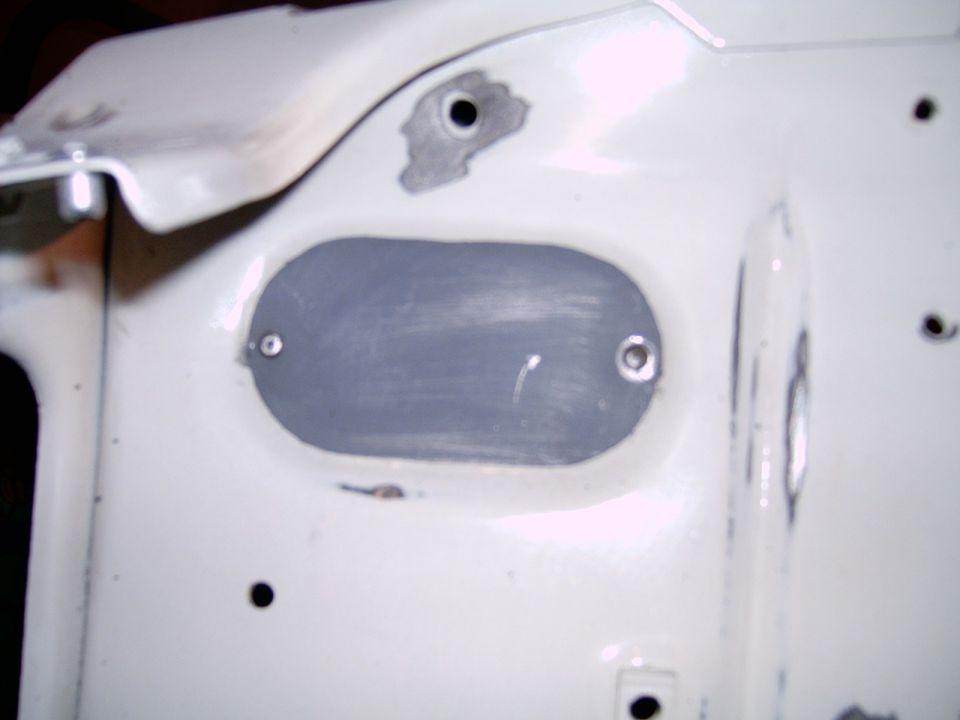 White car body panel with a grey oval-shaped insert secured by two screws