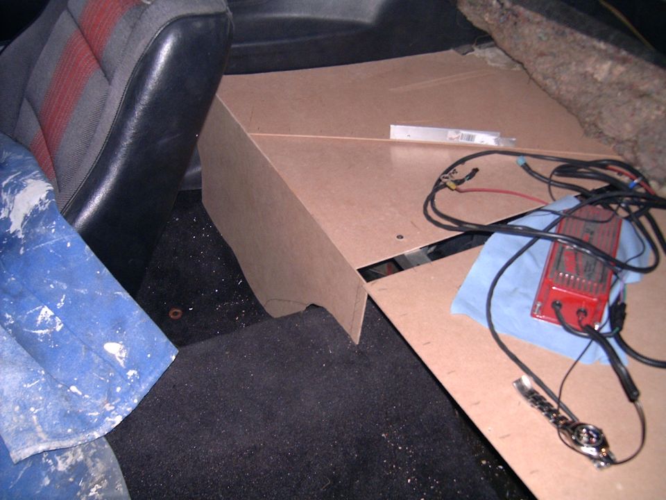 Car interior with custom-built MDF speaker box and wiring. Seat fabric has red stripes