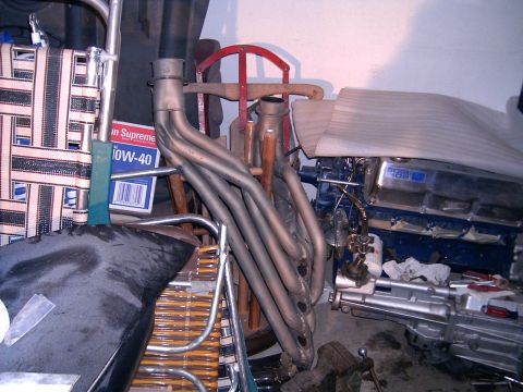 1978 Ford Mustang II - Engine components including headers and a V8 engine are stored indoors with other items.