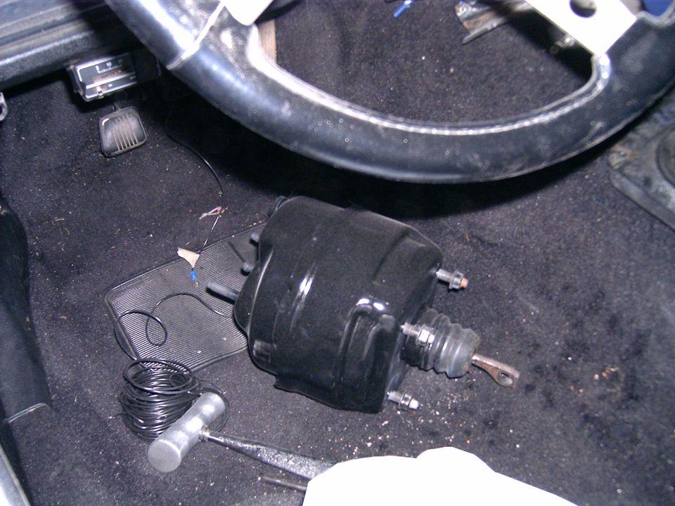 Black brake booster and steering wheel inside a car with black carpet