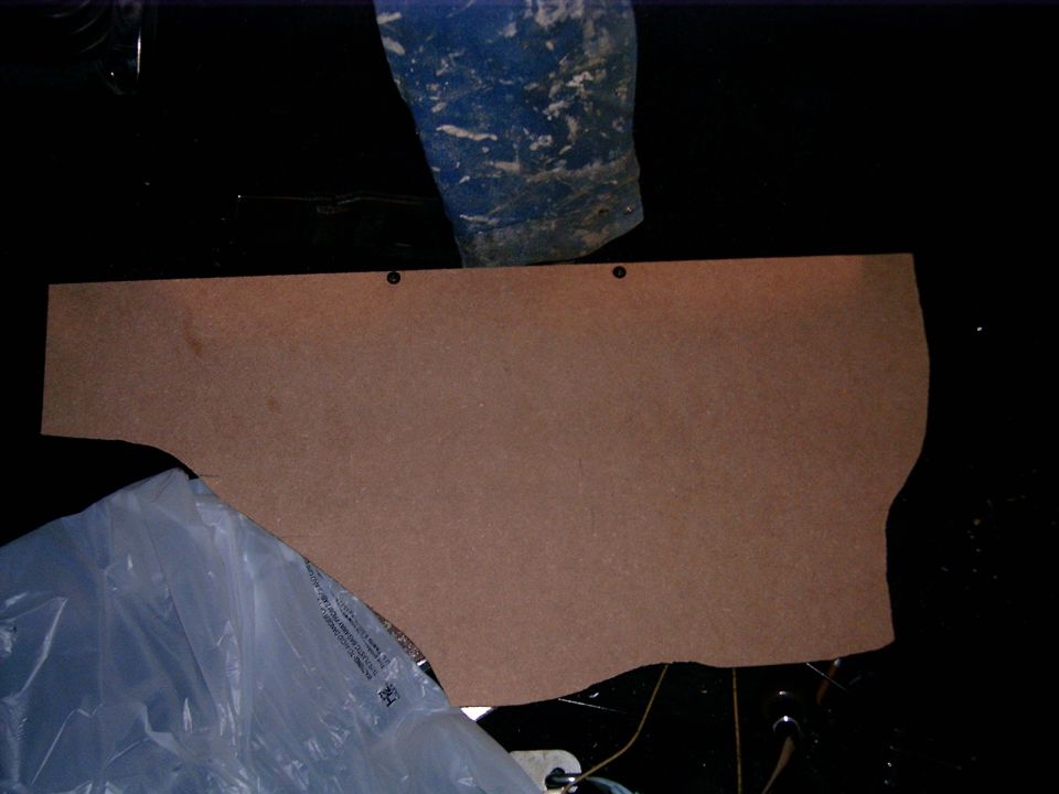 Cardboard panel with curved and straight edges, two screw holes visible