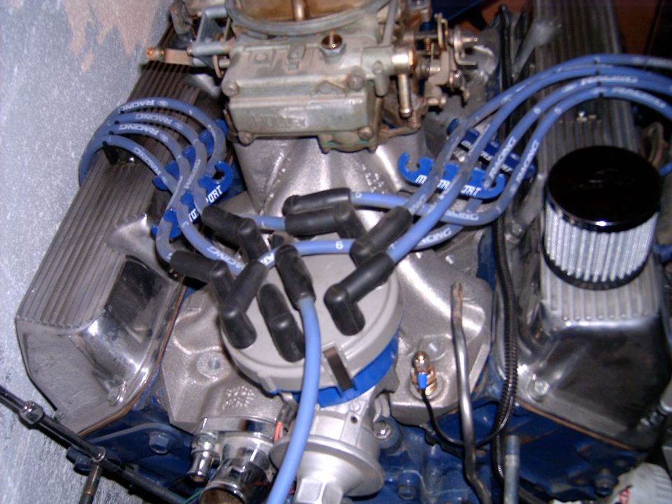 Close-up of a V8 engine with blue spark plug wires and a carburetor
