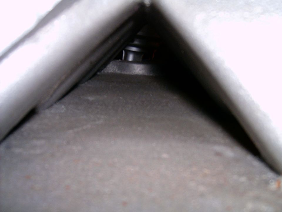 Close-up of a metal spring and surrounding components, likely part of a vehicle's suspension