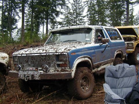 1985 Ford Bronco - This Bronco is covered in mud after an off-road excursion, with another vehicle visible in the background.