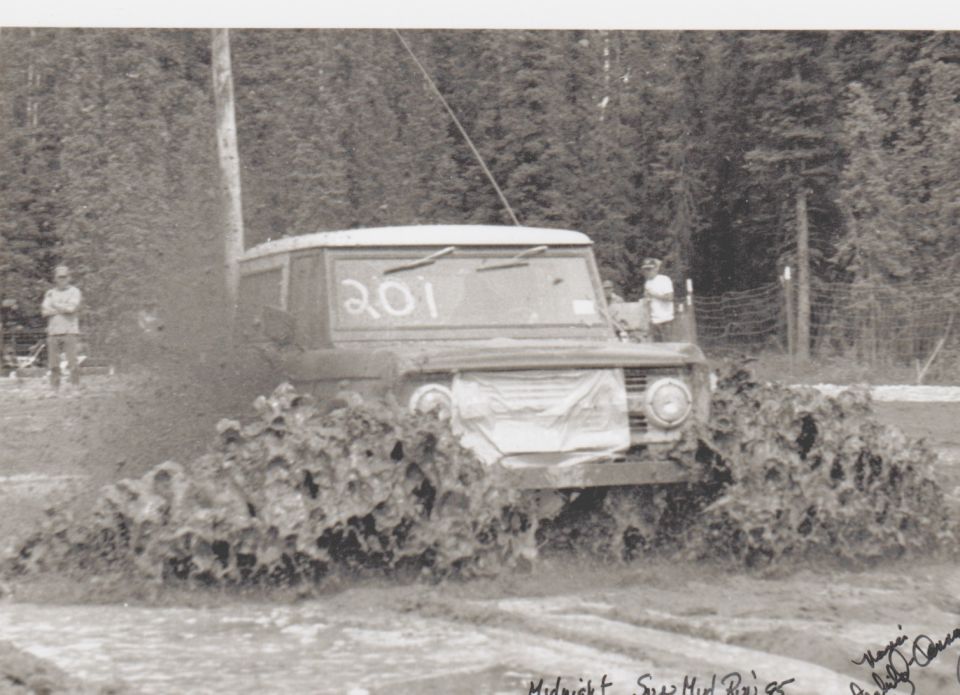 Off-road vehicle with number 201 on windshield driving through thick mud