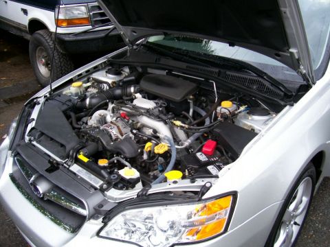 2001 Ford Crown Victoria - The engine bay of a silver Subaru is open, with a white Ford Explorer visible behind it.