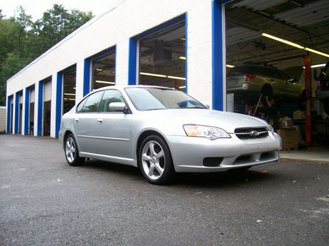 2001 Ford Crown Victoria - Silver Subaru Legacy sedan parked outside an auto repair shop with another car on a lift inside.