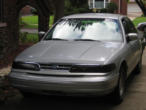 1996 Ford Crown Victoria - Silver sedan parked in a driveway, showing its front grille and headlights.