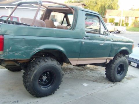 1989 Ford Bronco - This lifted Ford Bronco has a roll cage and aftermarket wheels, suggesting off-road modifications.