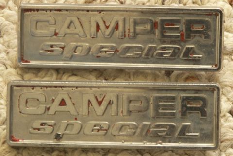 1978 Ford Bronco - A matched pair of chrome "CAMPER special" fender emblems laid on a cream-colored knit blanket, with red paint residue still clinging in the…
