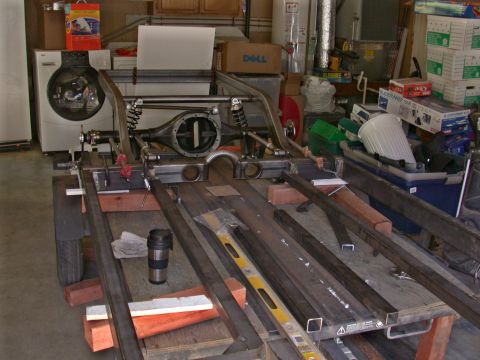 1964 Ford Ranchero - A disassembled vehicle chassis and rear axle assembly is shown in a workshop setting.
