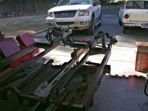 1964 Ford Ranchero - Custom chassis project in progress, with a white SUV and a pickup truck visible in the background.